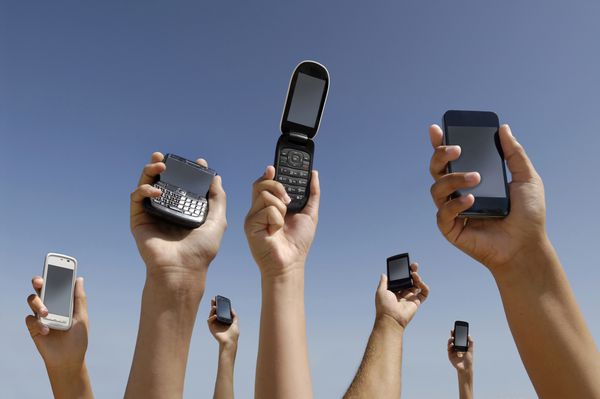گروهی از دست ها با تلفن های همراه مختلف در حال اتصال