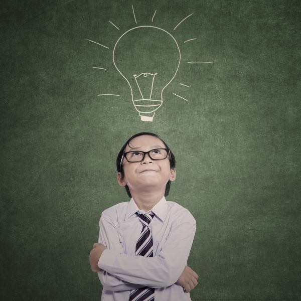 بچه تجاری آسیایی با لامپ دستی در کلاس فکر می کند