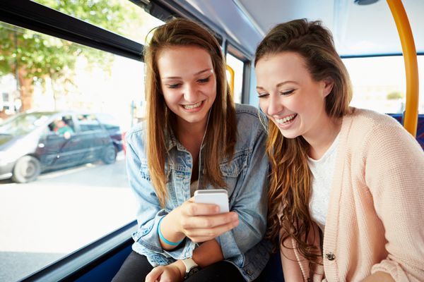 دو زن جوان در حال خواندن پیام متنی در اتوبوس