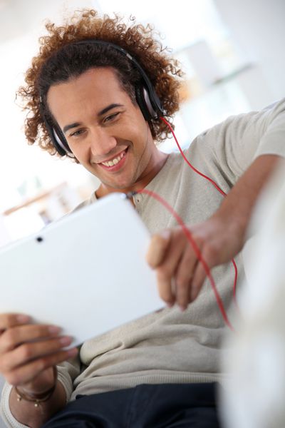 مرد خندان در حال گوش دادن به موسیقی با تبلت