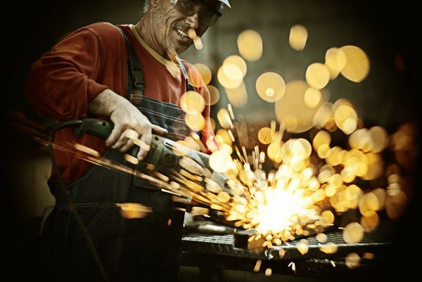 کارگر صنعتی برش و جوشکاری فلز با جرقه های تیز فراوان