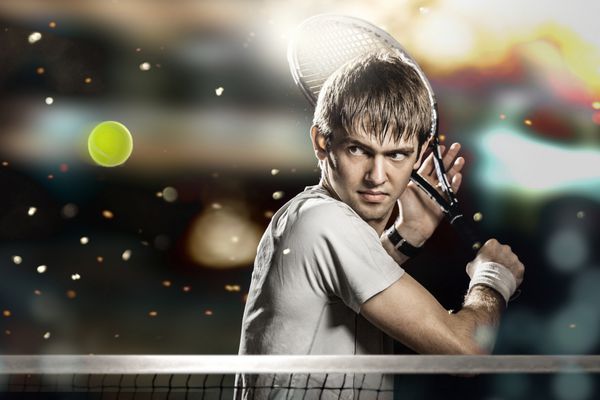 تنیس باز مرد جوان در حال ضربه زدن به توپ