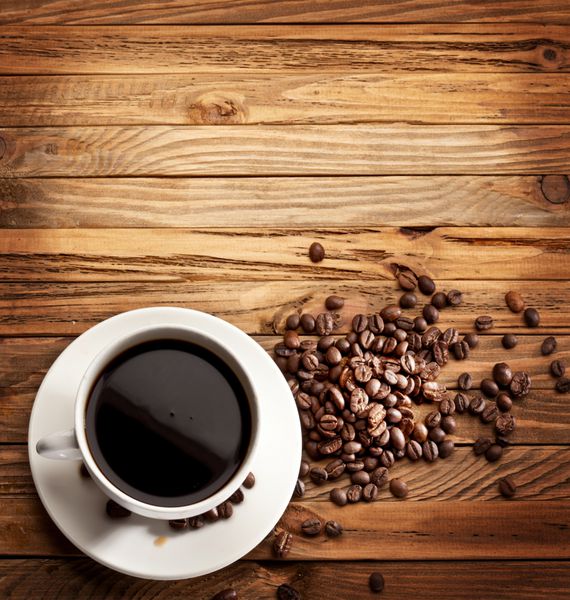 فنجان قهوه نمایی از بالا روی یک سطح چوبی