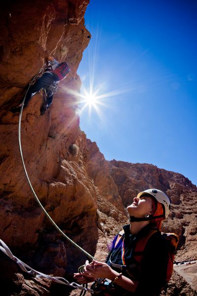 یک کوهنورد زن در حین صخره نوردی در دره تودرا اطلس ماروک آفریقا رهبر را تسلیم می کند