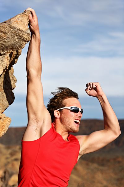 مفهوم موفقیت - مردی در حال بالا رفتن آویزان شدن روی لبه و نشان دادن قدرت و عضلات کوهنورد مرد موفق قوی