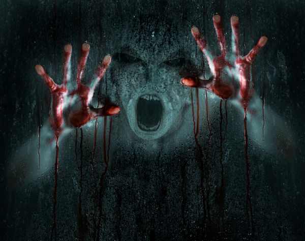 صحنه ترسناک تاریک از یک دیو یا زامبی با دست های خونین در برابر شیشه مرطوب یخی