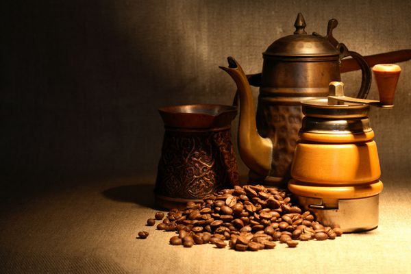 طبیعت بی جان قدیمی با انبوهی از دانه های قهوه در نزدیکی قهوه جوش مسی قدیمی