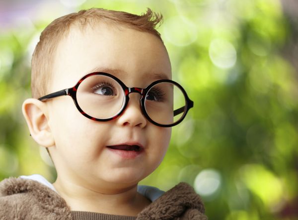 پرتره کودکی که عینک گرد بر روی پس زمینه طبیعت می پوشد