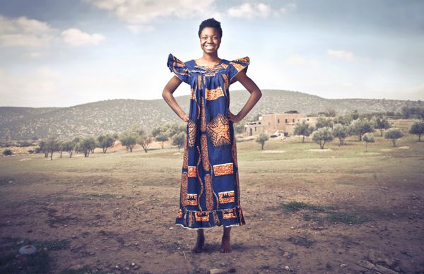 زن آفریقایی خندان با لباس های سنتی در مزرعه ای بیابانی
