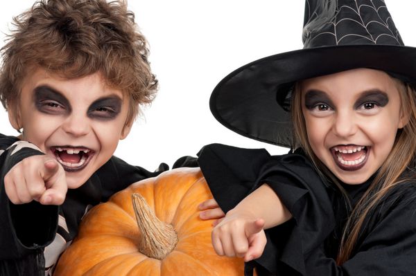 دختر و پسر با پوشیدن لباس هالووین با کدو تنبل در پس زمینه سفید