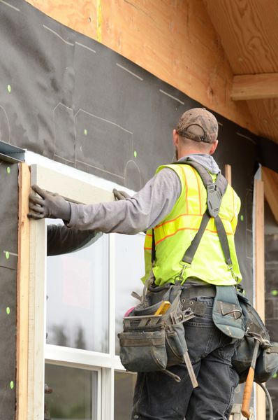 کارگر در حال نصب تزئینات اطراف یک پنجره قبل از قرار دادن دیوارپوش در یک ساختمان تجاری بزرگ در اورگان