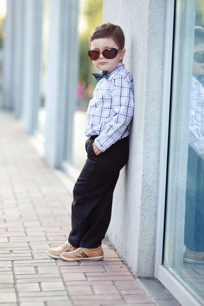 پسر بچه شیک و ناز به سبک کلاسیک در شهر با عینک آفتابی