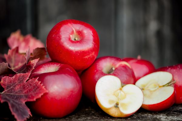 سیب تازه ارگانیک در زمینه چوبی در برداشت پاییز در مزرعه محلی موضوع مفهومی کشاورزی با سیب تازه در طبیعت