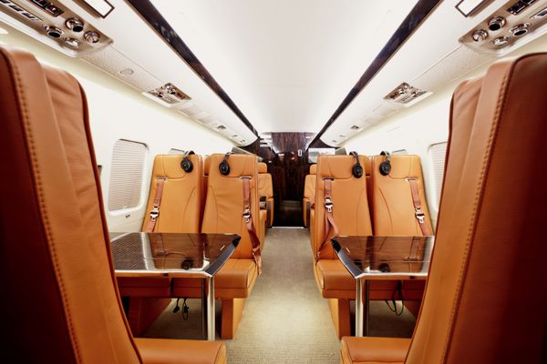 داخلی هواپیمای خصوصی با میزهای چوبی و صندلی های چرمی