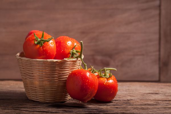 گوجه فرنگی آبدار قرمز در سبد روی میز چوبی