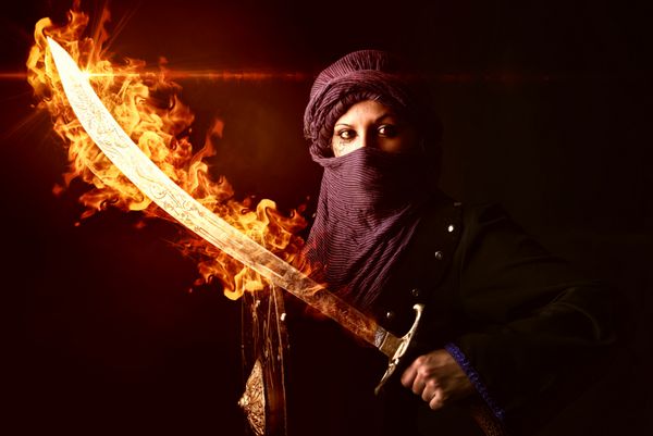 زن جنگجوی عربی با شمشیر در آتش در پس زمینه ای تاریک