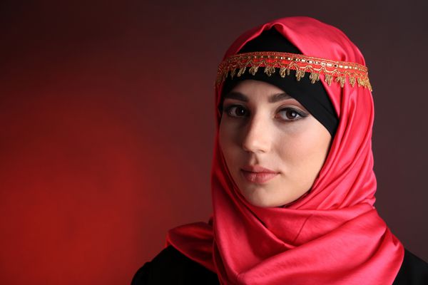 زن مسلمان عربی زیبا در زمینه رنگ تیره