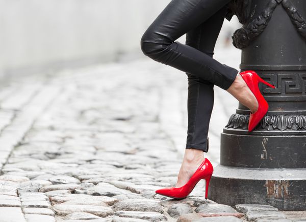 زنی با شلوار چرمی مشکی و کفش پاشنه بلند قرمز در شهر قدیمی