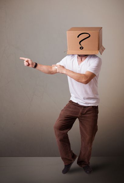 مرد جوانی ایستاده و با یک جعبه مقوایی روی سرش با علامت سوال اشاره می کند