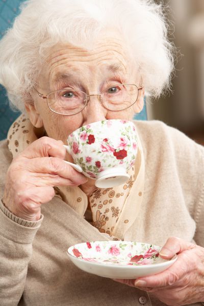 زن مسن در حال لذت بردن از فنجان چای در خانه