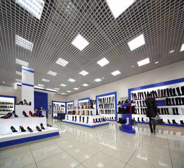 فروشگاه کفش های روشنایی جادار داخل با مدل هایی روی قفسه های سفید