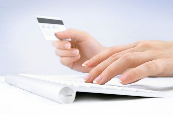 دست های زنی که کارت اعتباری را در دست گرفته و از صفحه کلید کامپیوتر برای خرید آنلاین استفاده می کند