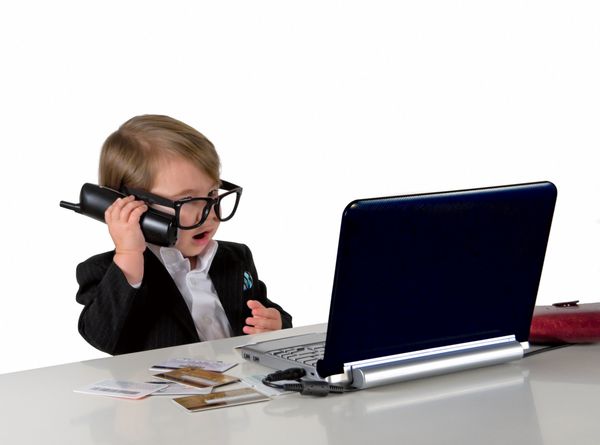 یک دختر کوچک پسر در حال تماس با تلفن کت و شلوار مشکی و عینک کامپیوتر کارت های اعتباری روی میز هستند مفهوم کسب و کار شی ایزوله