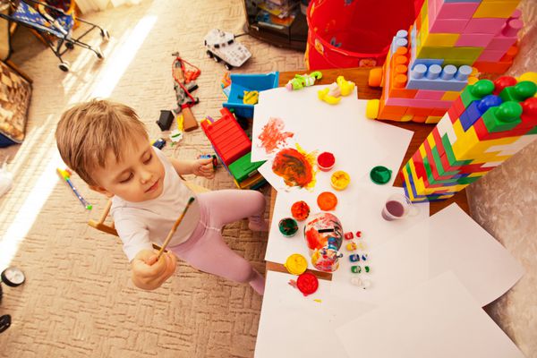 کودک در مهدکودک آبرنگ های رنگی می کشد پسر کوچکی که در اتاق بازی می کند