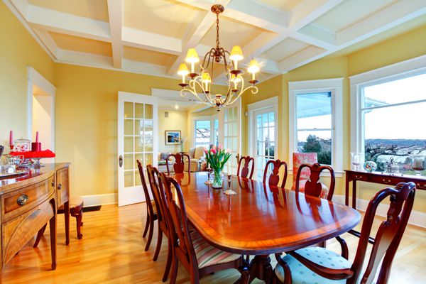 اتاق ناهارخوری لوکس زرد روشن طلایی با مبلمان کلاسیک ظریف و سقف چوبی سفید