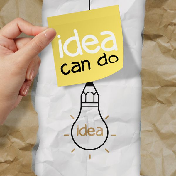 دست نگه داشتن یادداشت چسبناک با ایده می تواند لامپ کلمه را روی کاغذ مچاله شده به عنوان یک ایده خلاقانه انجام دهد