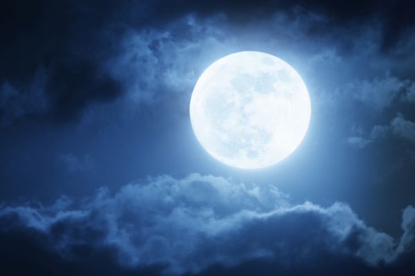 تصویر دراماتیک از آسمان شب با ابرهای روشن و ماه کامل بزرگ و درخشان پس‌زمینه‌ای عالی ایجاد می‌کند