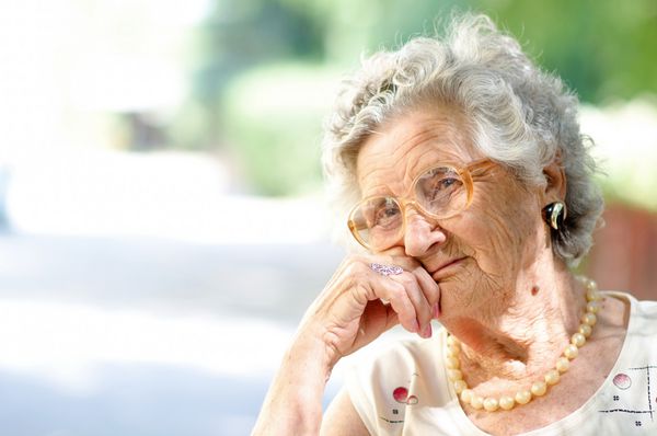 پرتره زن مسن خندان نشسته در فضای باز