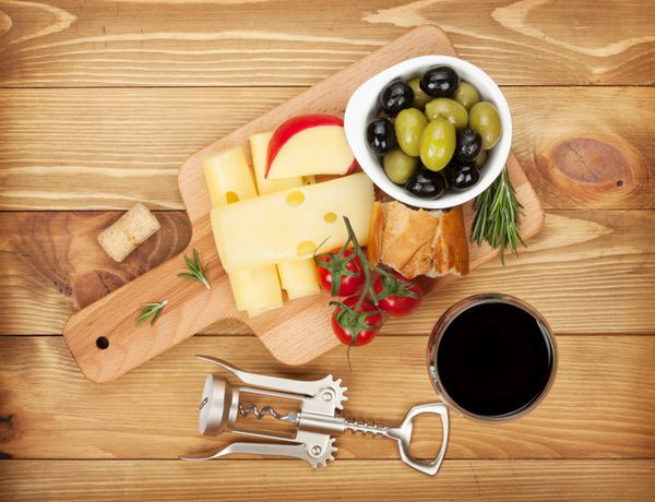 شراب قرمز با پنیر نان زیتون و ادویه جات ترشی جات روی پس زمینه میز چوبی نمای از بالا