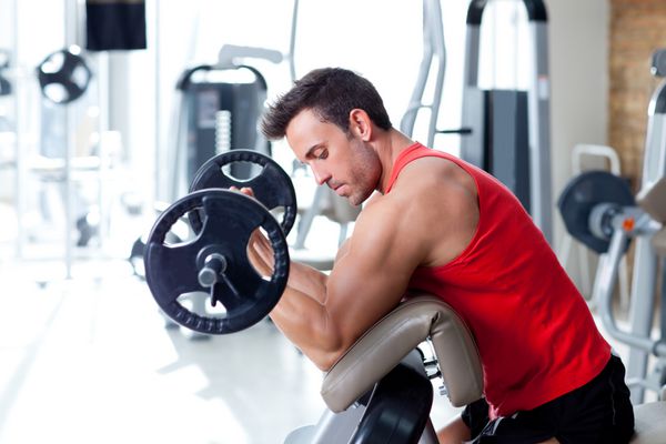 مردی با تجهیزات تمرین وزنه در سالن ورزشی