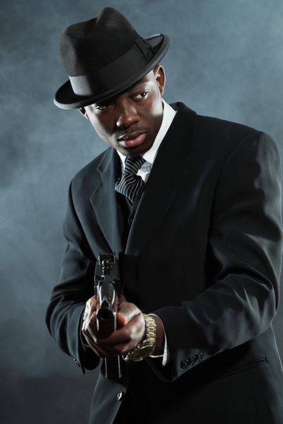 مرد گانگستر مافیای سیاه پوست آمریکایی در کت و شلوار با تفنگ