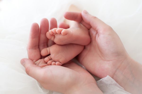دست های زنانه که پای نوزاد را گرفته اند