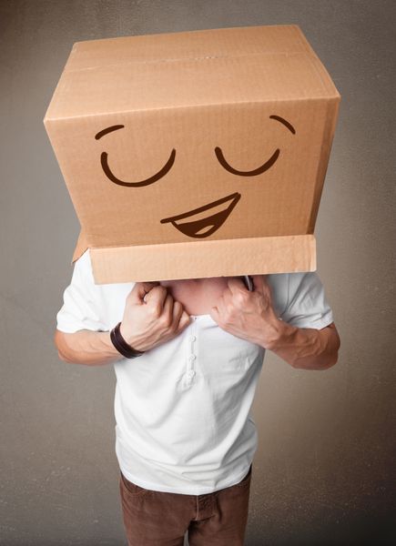 مرد جوان با یک جعبه مقوایی روی سرش با شکلک اشاره می کند