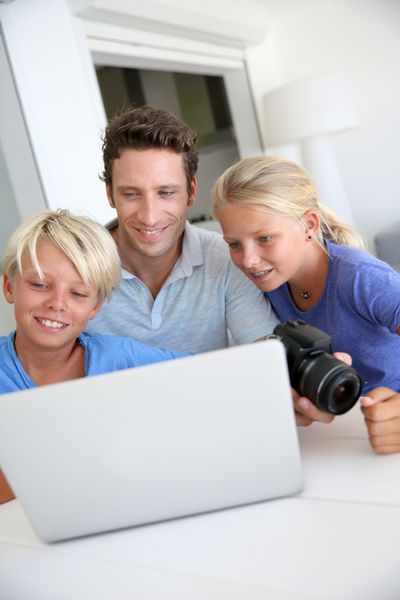 مردی با نوجوانان در حال تماشای تصاویر در رایانه