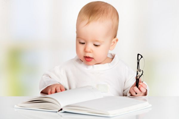 کودک بامزه در حال خواندن کتاب