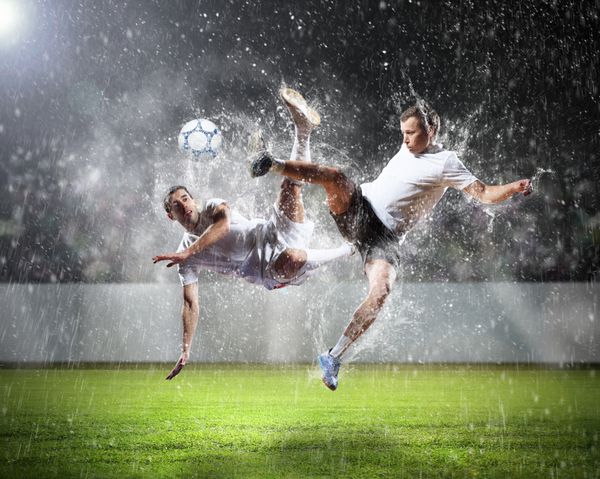 دو بازیکن فوتبال در حال ضربه زدن به توپ