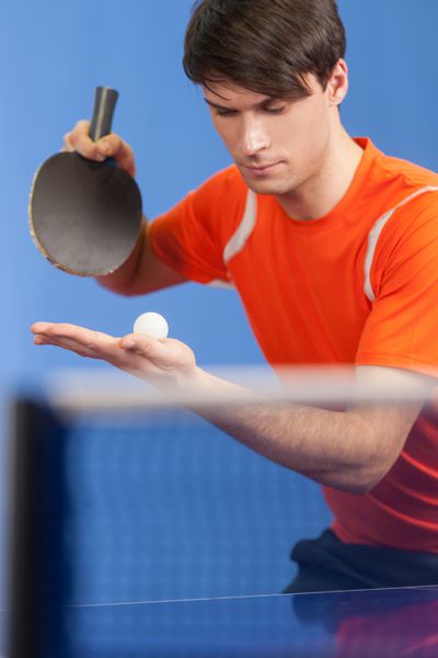 سرو کردن یک توپ مردان جوان با اعتماد به نفس در حال بازی تنیس روی میز