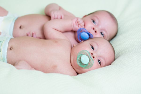 دوقلوهای بامزه نوزاد تازه متولد شده که کنار هم دراز کشیده اند