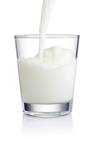 ریختن یک لیوان شیر تازه جدا شده در زمینه سفید