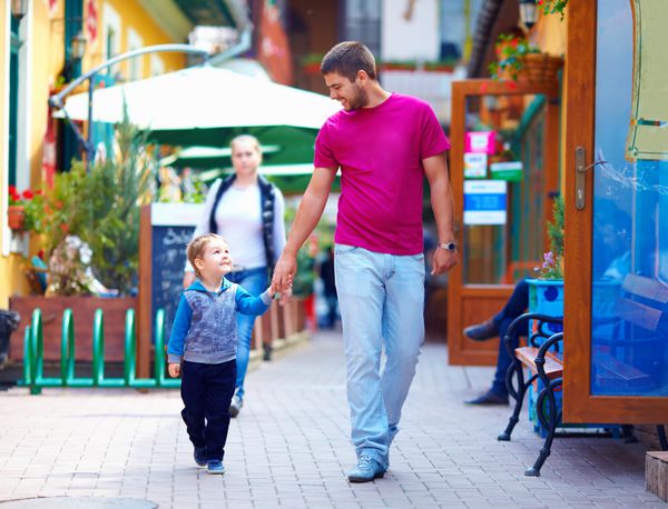 پدر و پسر شادی که در خیابان شهر قدم می زنند