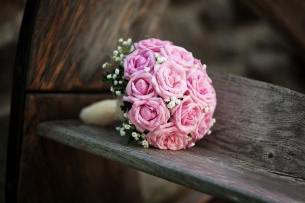 دسته گل عروس رز صورتی روی نیمکت چوبی