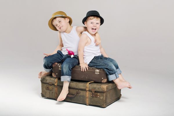 دو برادر کوچک روی چمدان ها نشسته اند