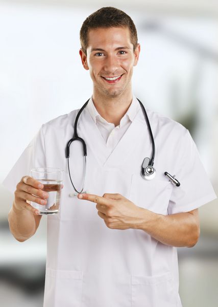 مرد دکتر جوان با گوشی پزشکی که یک لیوان آب را نشان می دهد