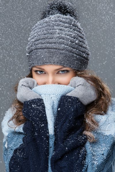 دختر زیبا در لباس زمستانی با دانه های برف