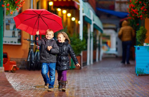 بچه های شادی که در خیابان زیر باران می دوند