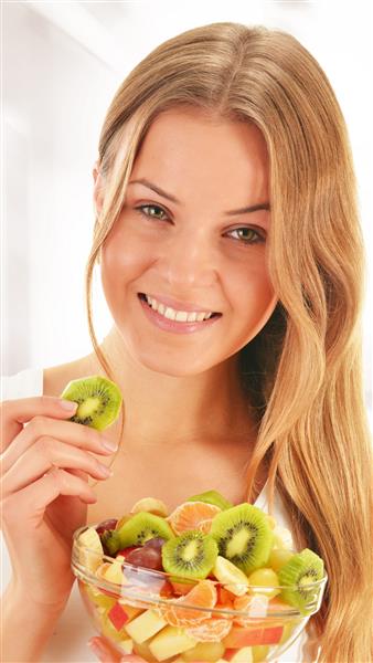 زن جوان در حال خوردن سالاد میوه